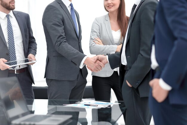 Two cheerful businessmen shaking hands with smile at office with