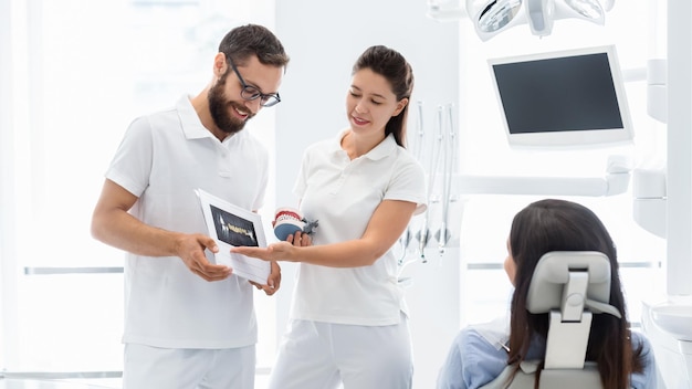 Photo two cheerful dentists explaining teeth disease treatment to patient