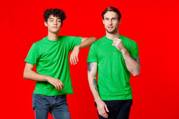 Two cheerful friends in green tshirts joy of communication red background