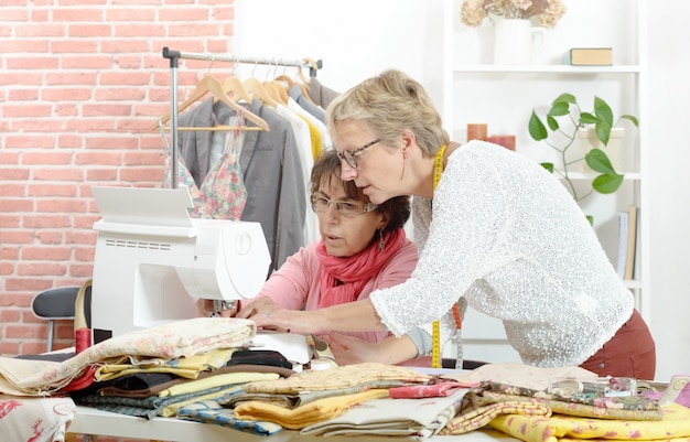 Two cheerful seamstresses working together in their workshop