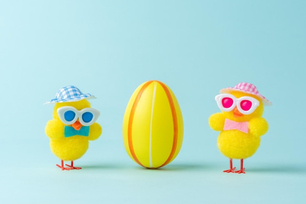 Two chickens with colorful easter egg on blue background