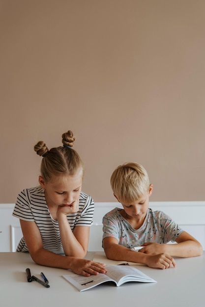 two children are sitting on a bed and one is looking at a phone