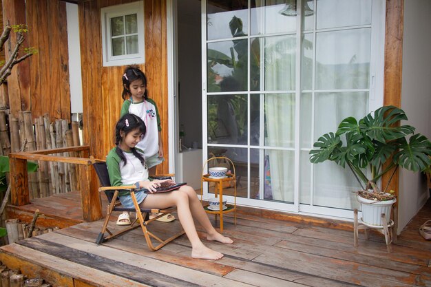 Photo two children are sitting on a porch with a girl reading a book