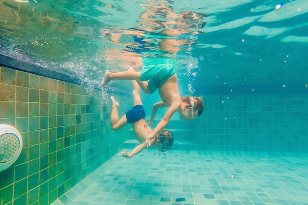 Two children diving in masks underwater in pool.