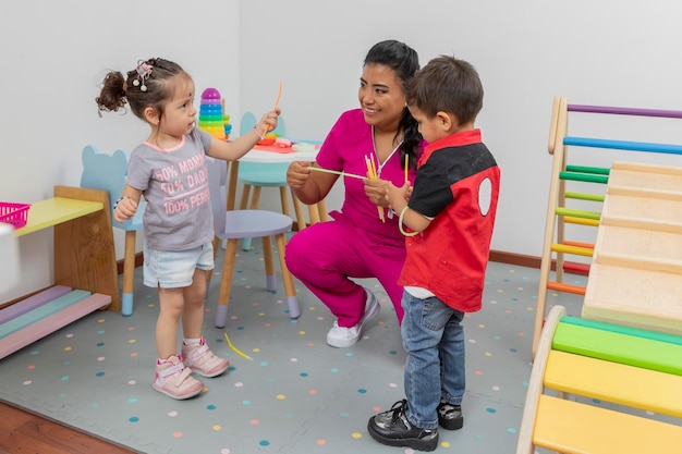 Two children play with the pediatrician doctor in the playground of the medical office