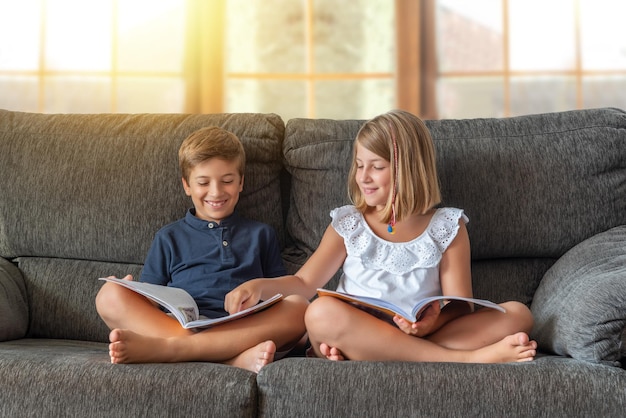 Two children reading and studying on the sofa at home Back to school Kids doing homework