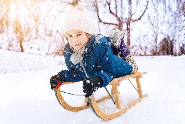 Two children ride on wooden retro sled on sunny winter day active winter outdoors games winter