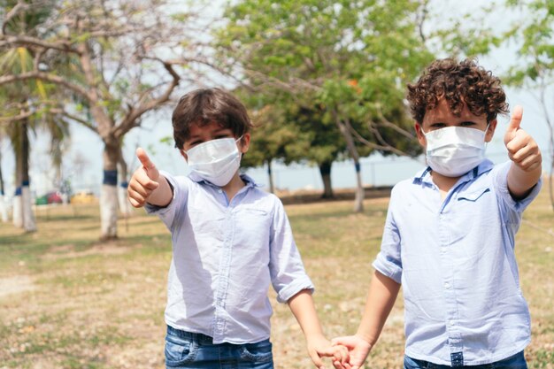 Two children with protective masks in the park