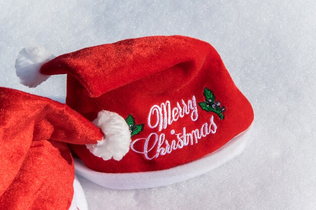 Two Christmas red hats on the white snow holiday celebration concept