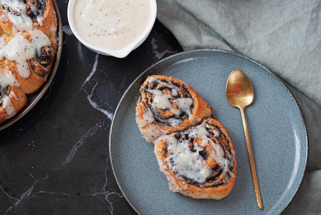 Two cinnamon rolls on a plate with a gold spoon next to it.