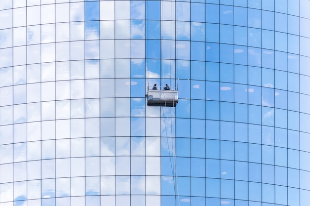 Two cleaners washing the windows of modern skyscraper