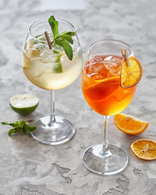 Two cocktails with lime and ice over grey background