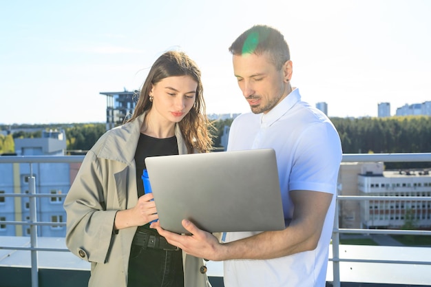 Two colleagues are studying the project on a laptop on the roof