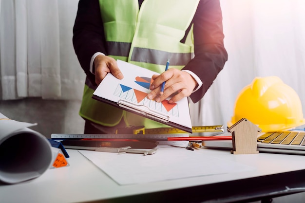 Two colleagues discussing data working and tablet laptop with on on architectural project at construction site at desk in office