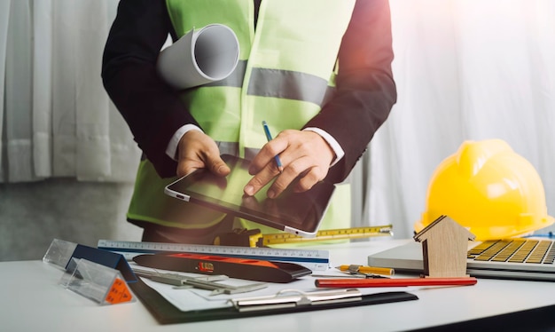 Two colleagues discussing data working and tablet laptop with on on architectural project at construction site at desk in office