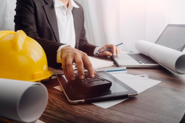 Two colleagues discussing data working and tablet laptop with on on architectural project at construction site at desk in office