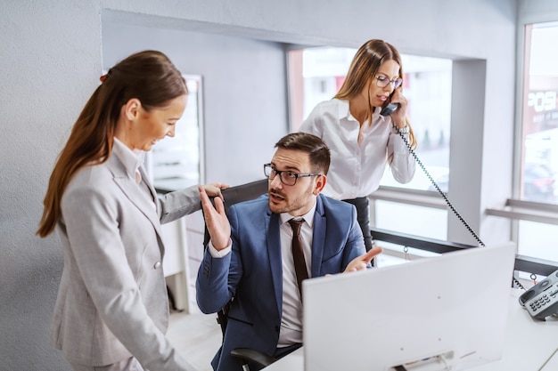 Two colleagues talking about solving the problem while secretary answering the phone