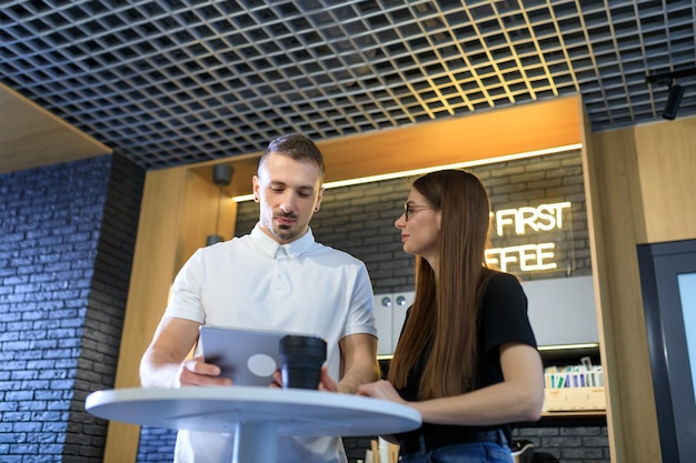 Two colleagues work during a coffee break with a tablet