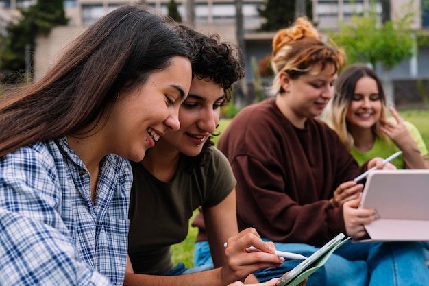 Two college students using a tablet on campus grass