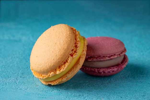 Two colored macaroons lie on a blue background selective focus