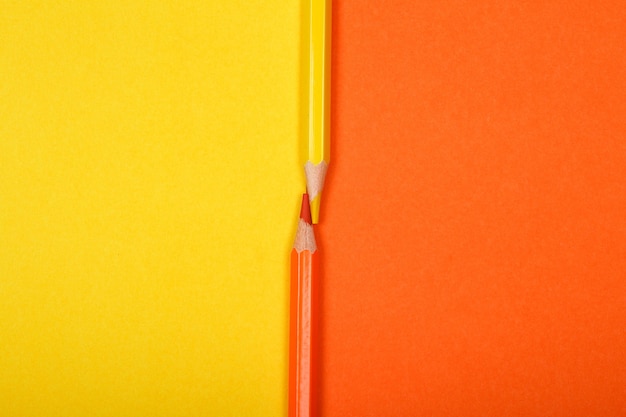 Two colored pencils isolated on two different color papers background