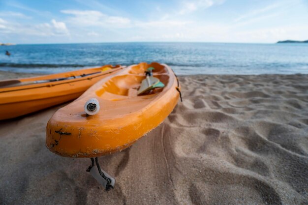 Two colorful orange kayaks on a sandy beach ready for paddlers in sunny day