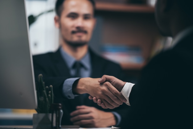 Two confident business man shaking hands during a meeting in the office, success, dealing, greeting and partner concept.