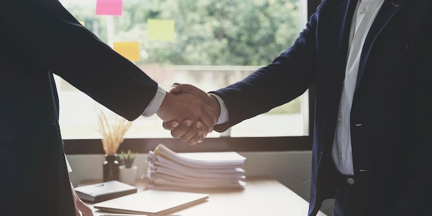 Two confident business man shaking hands during a meeting in the office success dealing greeting and partner concept