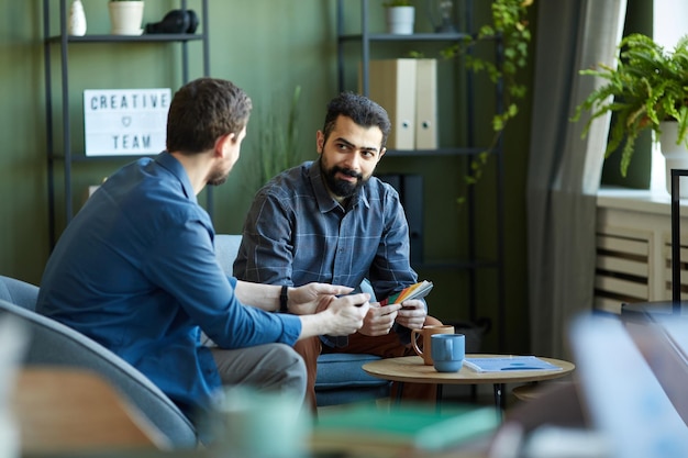 Two confident male designers or other specialists in smart casualwear discussing points of new creat