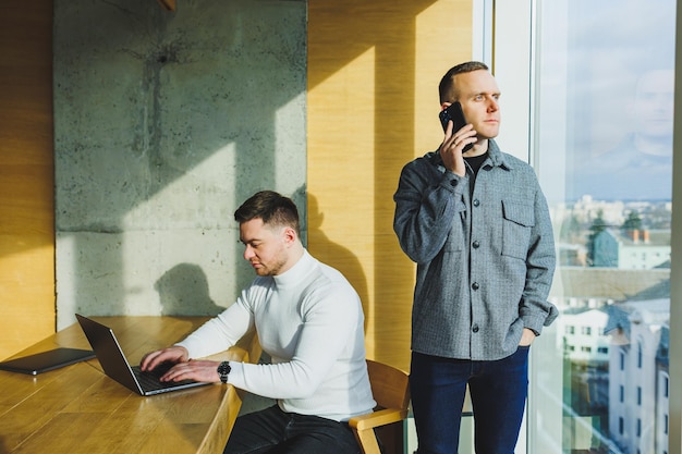 Two confident young people are sitting together at a table and one of them is pointing at a laptop Work on a new project Successful colleagues working together in the office