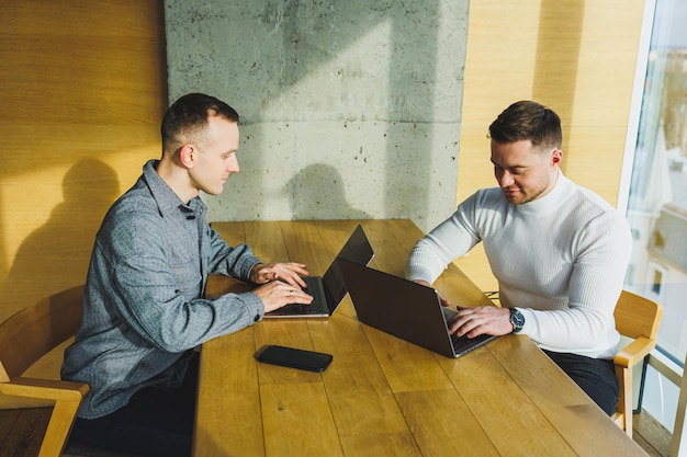 Two confident young people are sitting together at a table and one of them is pointing at a laptop Work on a new project Successful colleagues working together in the office