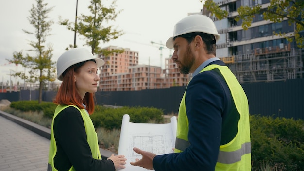 Photo two contractors civil engineers checking information in blueprint discuss teamwork pointing city buildings project managers planning collaboration construction workers with plan for urban development