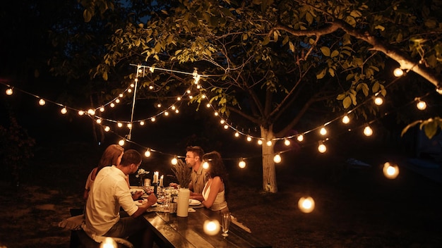 Two couples having romantic dinner in a backyard