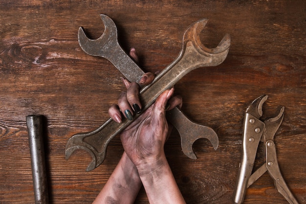 Two crossed spanners on wooden background in woman's hands. Service repair and maintenance concept