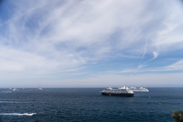 Two cruise ships at sea during sunny day surrounded by lots of powerboats. Monte Carlo, Monaco.