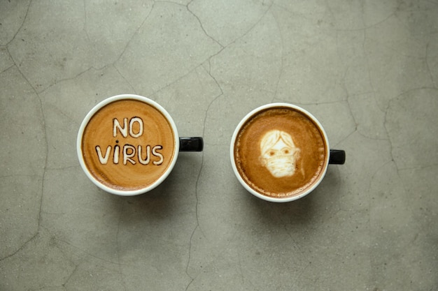 Two cup of Cappuccino with latte art man in facial mask and sign No virus