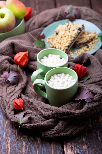 Two cup of coffee or hot chocolate with marshmallow near knitted blanket and pie.