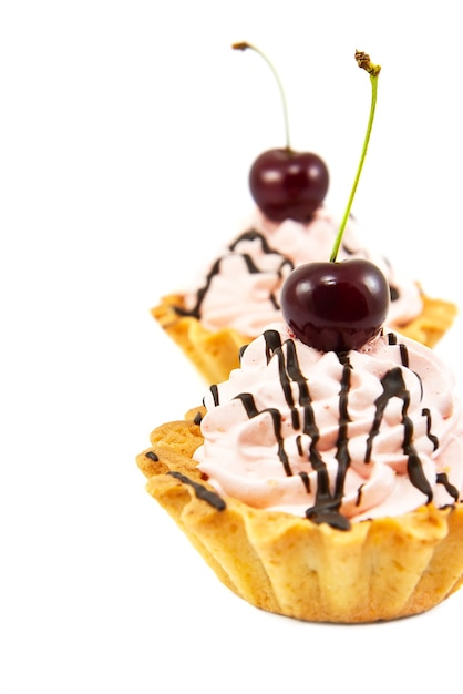 Two cupcakes with whipped cream and cherry isolated on white