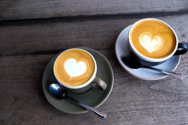 Two cups of coffee on black rustic background with beautiful latte art