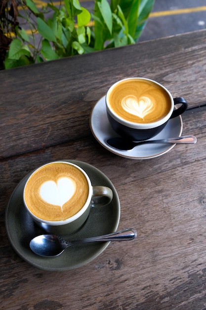 Two cups of coffee on black rustic background with beautiful latte art