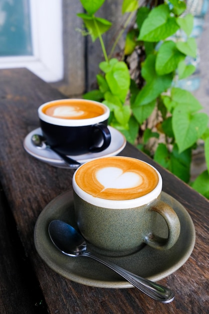 Two cups of coffee on black rustic background with beautiful latte art