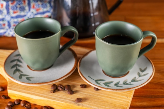 two cups of coffee and strainer used in the background