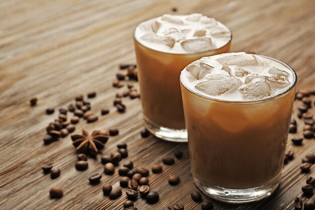 Two cups of ice coffee with coffee beans on wooden table