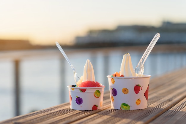 Two cups of ice cream with candies on sunset.