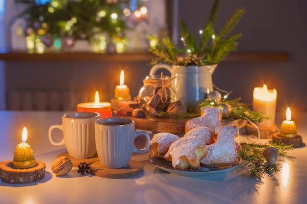 Two cups of tea with homemade christmas baked goods on kitchen with christmas decoration