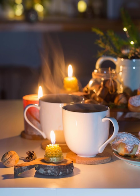 Two cups of tea with homemade christmas baked goods on kitchen with christmas decoration