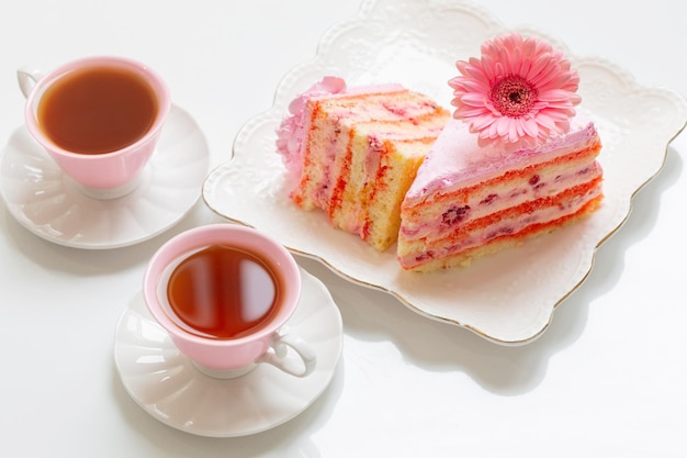 Two cups of tea with pink cake on white table