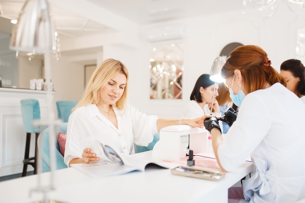 Two customers on manicure procedure in beauty salon.