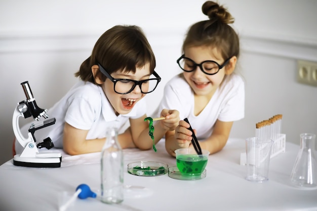 Two cute children at chemistry lesson making experiments isolated on white background