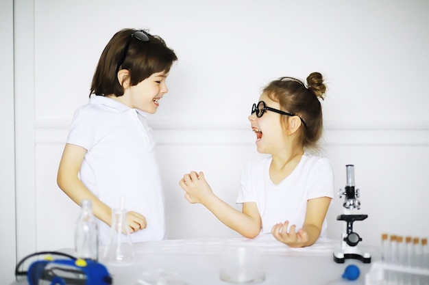 Two cute children at chemistry lesson making experiments on white background